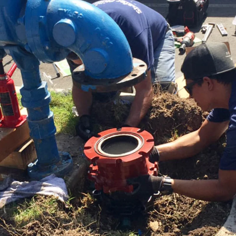 Technicians fitting a Smart Valve into an excavated supply line
